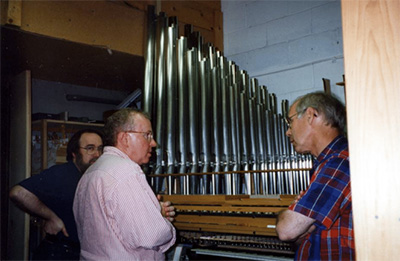 James Louder and two other men talking by the organ